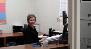 A woman sitting at her desk smiling for the camera.