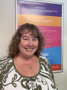 A woman smiling in front of a poster.