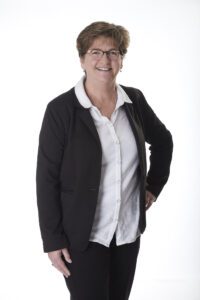 A woman in glasses and black jacket posing for the camera.