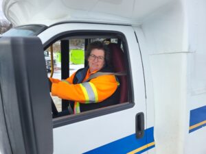 A man in an orange vest driving a van.