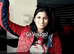 A woman in red jacket and sunglasses smiling for the camera.